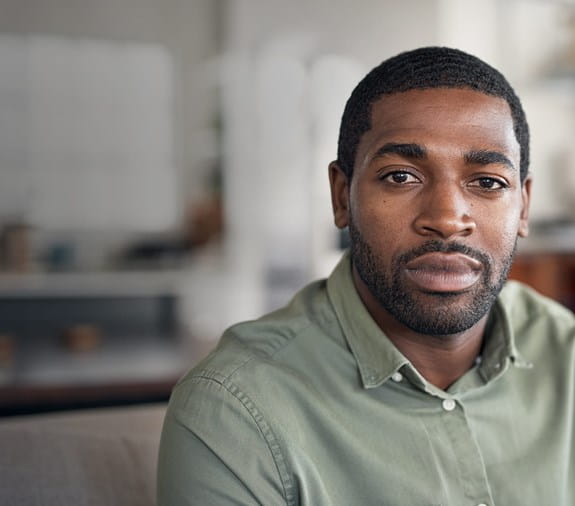 A young black man sitting in his home.