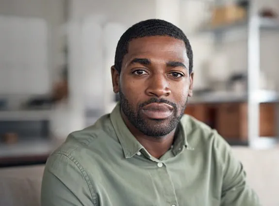 A young black man sitting in his home.