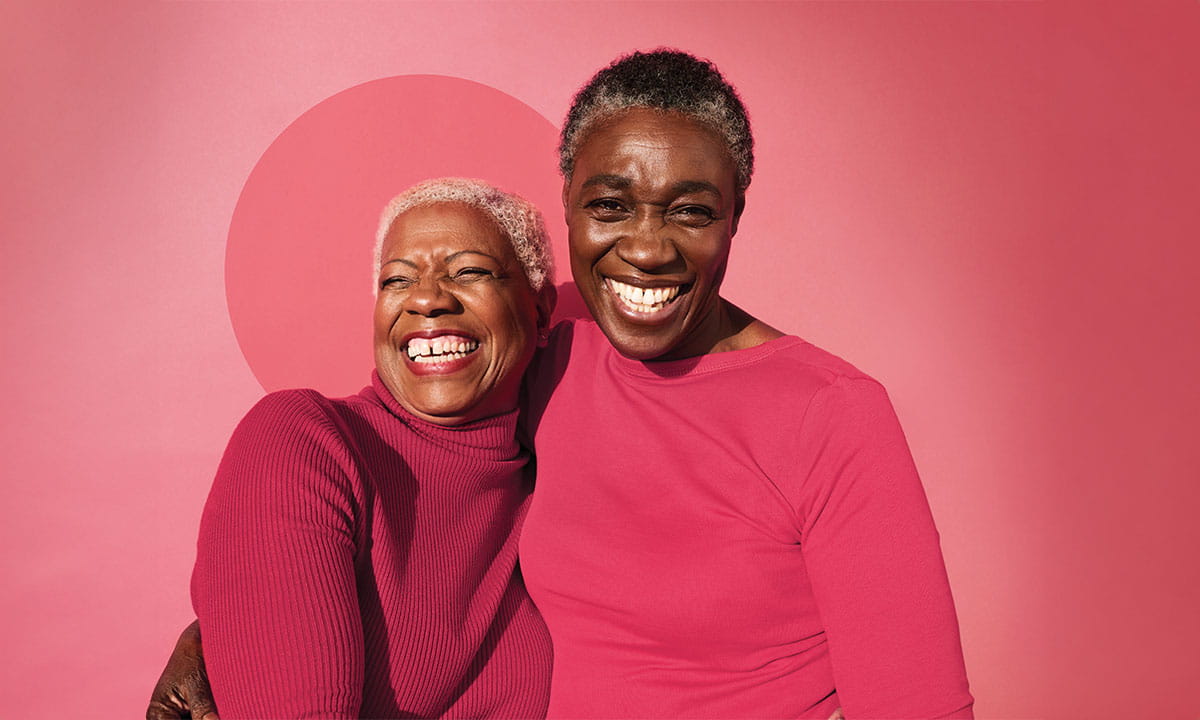 Two laughing women sitting close together.