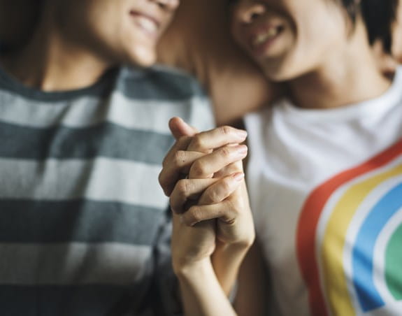 An LGBTQ couple holding hands and smiling