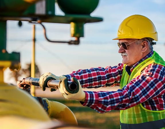 Construction worker outside wearing sunglasses, long sleeves and helmet