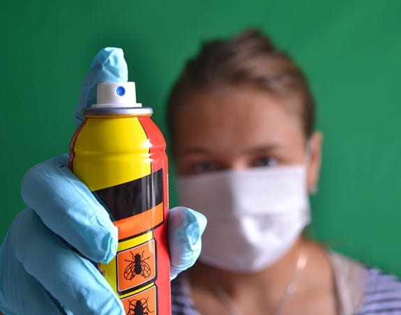 Person wearing a mask holding a can of bug spray
