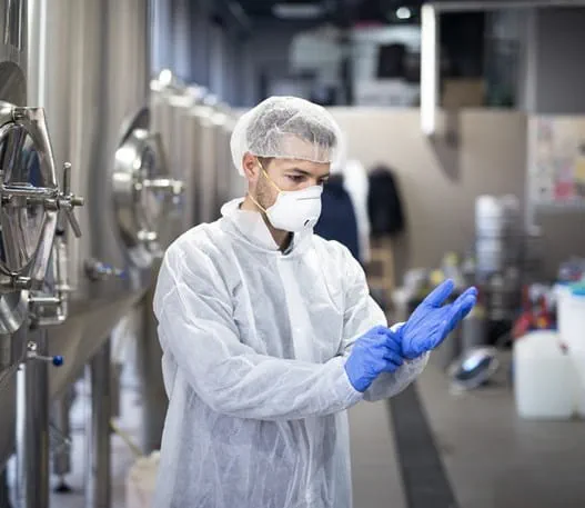 Manufacturing worker wearing a protective suit, mask and gloves