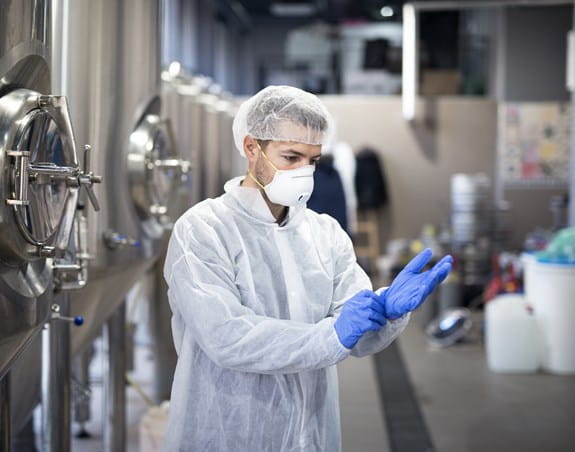 Manufacturing worker wearing a protective suit, mask and gloves