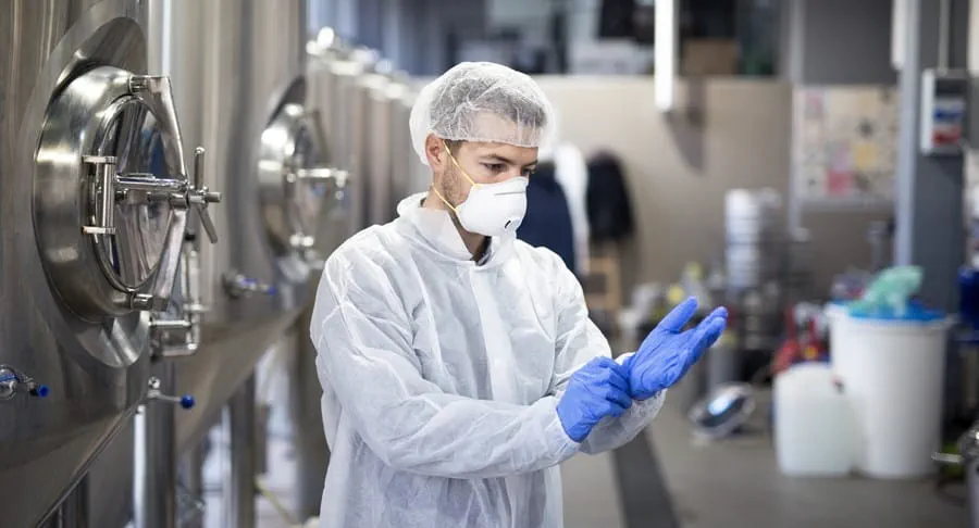 Manufacturing worker wearing a protective suit, mask and gloves