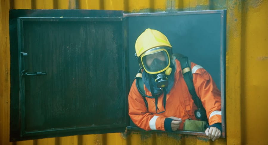 Firefighter in full gear and oxygen mask in a smokey area