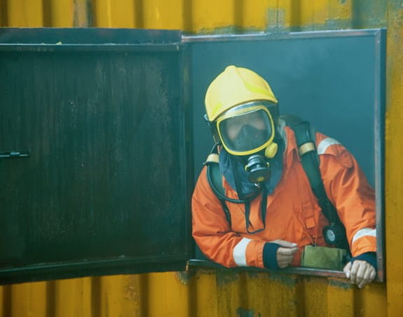 Firefighter in full gear and oxygen mask in a smokey area