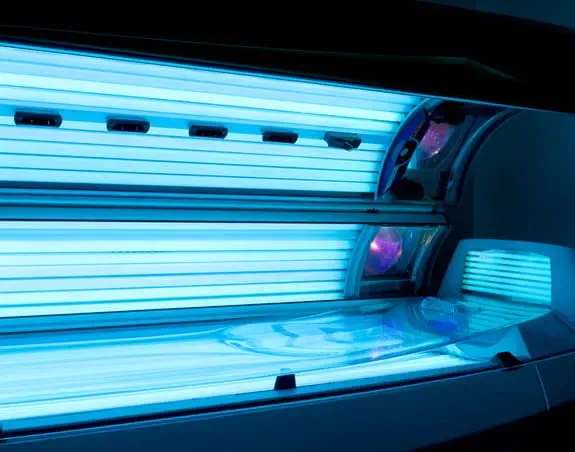 Open tanning bed with blue UV light showing