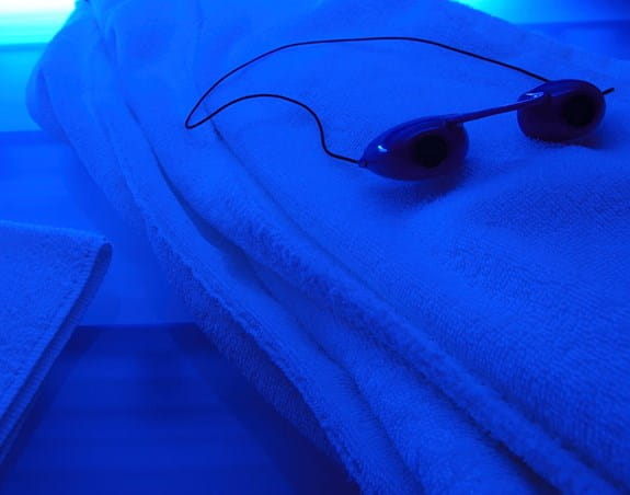 Tanning goggles on a towel with blue UV light from a tanning bed