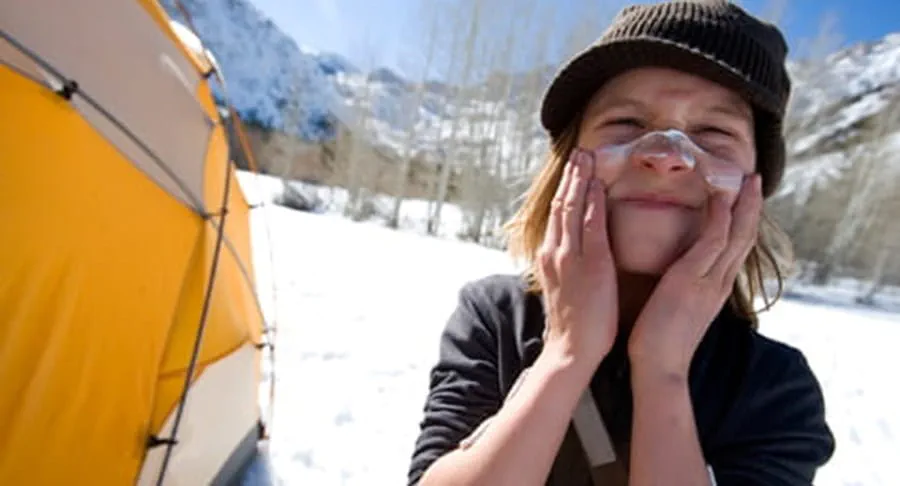 Child putting on sunscreen at a campsite in the winter