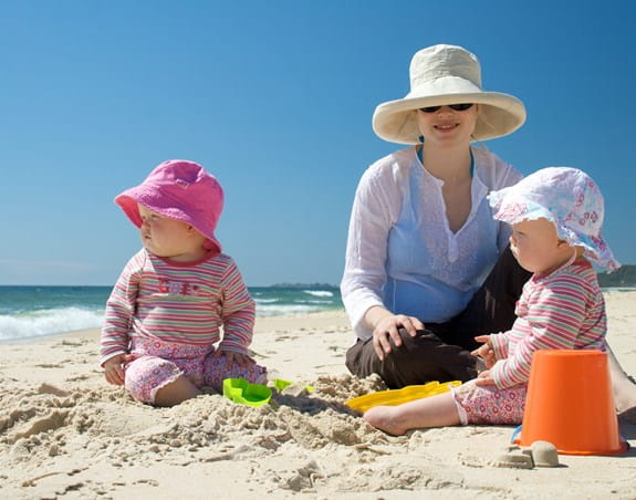 Parent with two babies on a beach
