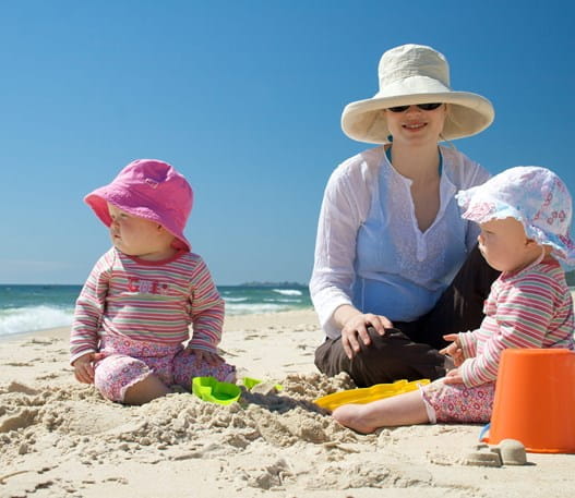 Parent with two babies on a beach