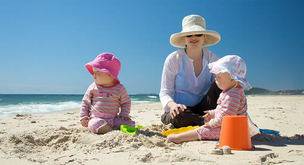 Parent with two babies on a beach