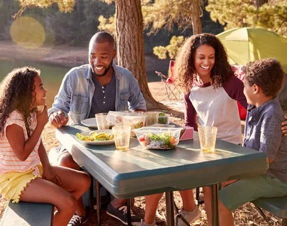 Une famille mangeant en plein air, à une table de pique-nique