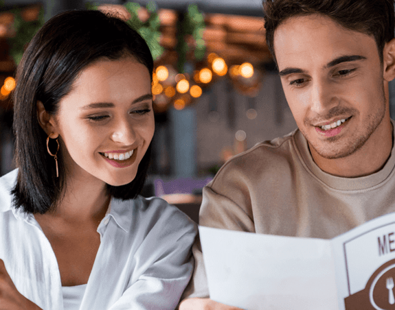 Two people reading from a restaurant menu