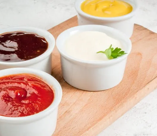 Small bowls of ketchup, mustard and other condiments