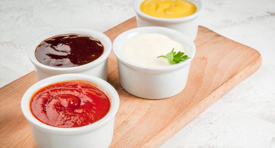 Small bowls of ketchup, mustard and other condiments