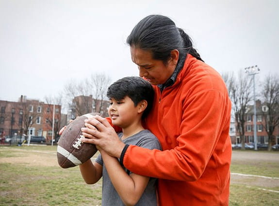 Un père apprend à son fils à lancer un ballon de football