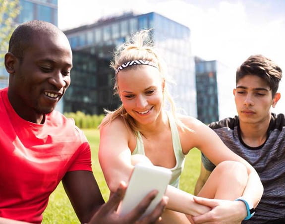 Teenagers sitting outside looking at a cellphone