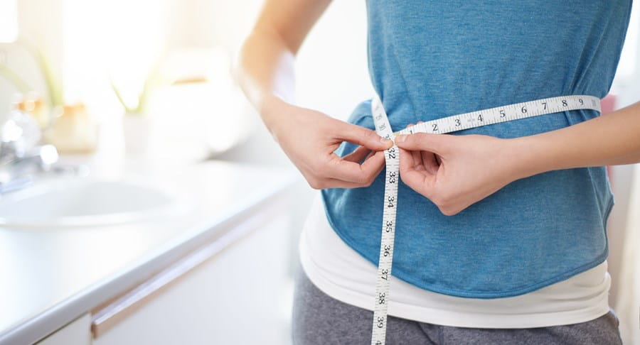 Une personne mesurant son tour de taille au moyen d’un ruban à mesurer