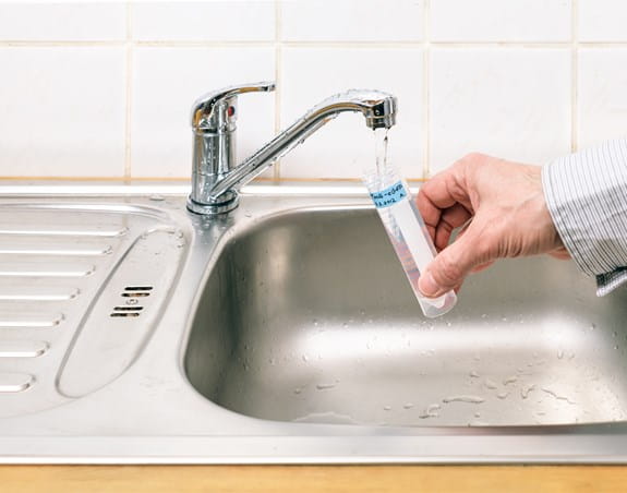 Une personne faisant un test d’eau du robinet pour vérifier la présence d’arsenic