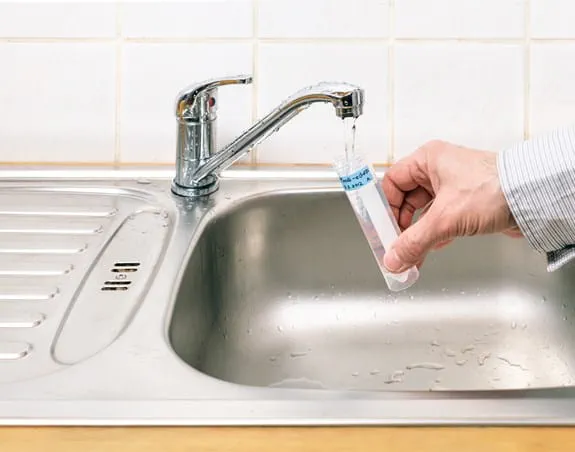 Une personne faisant un test d’eau du robinet pour vérifier la présence d’arsenic