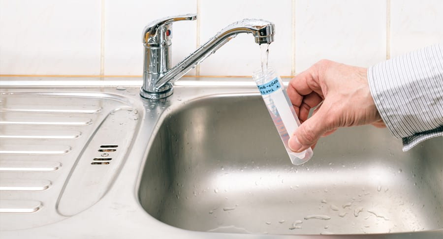Person testing tap water in their home for arsenic