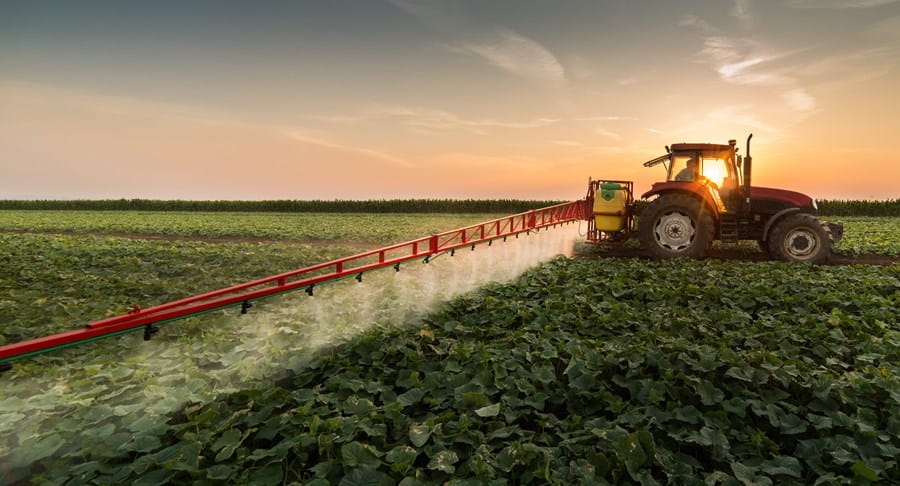 Tractor spraying crops with pesticides