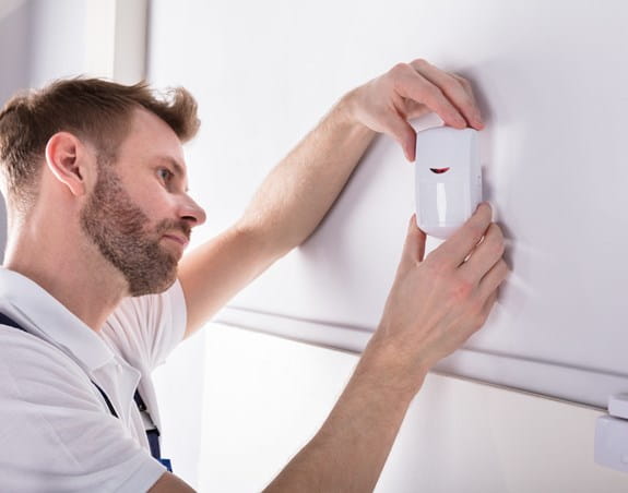 Technician installing a radon detector in someone's home 