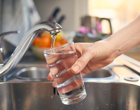 Person filling up a glass with tap water