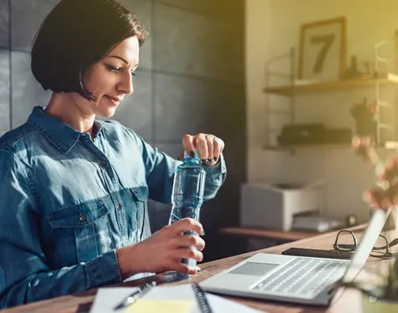 Person opening a reusable water bottle at their desk