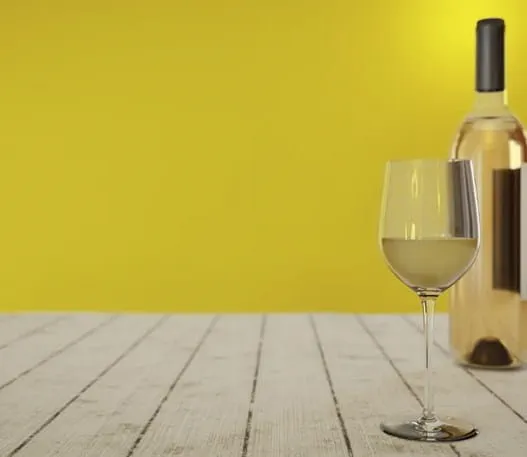 A glass of white wine next to a bottle of white wine