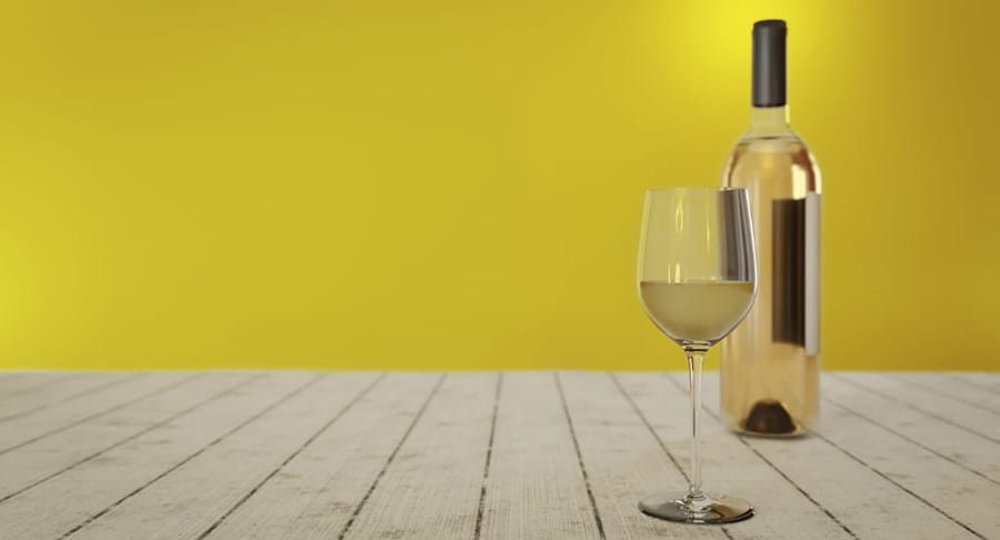 A glass of white wine next to a bottle of white wine