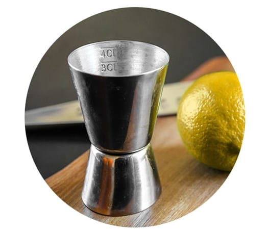 A shot glass next to a lime