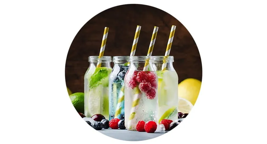 Four mocktails on a table with berries and other fruit