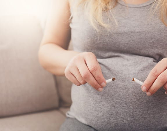 A pregnant woman breaking a cigarette