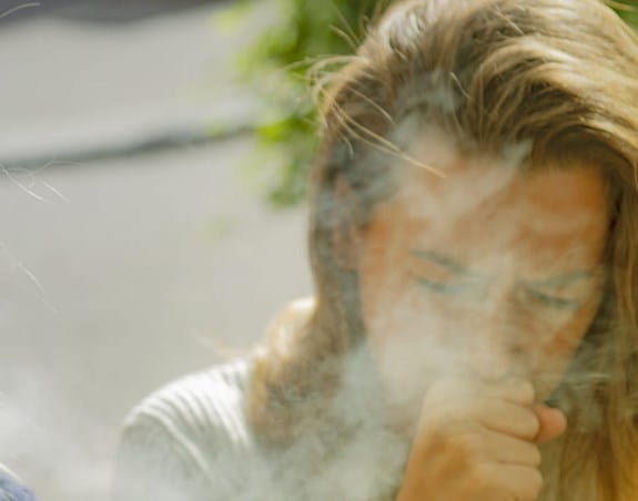 Person coughing from breathing in second-hand smoke