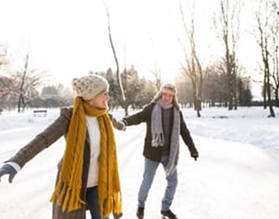 Two people skating outside in the winter holding hands
