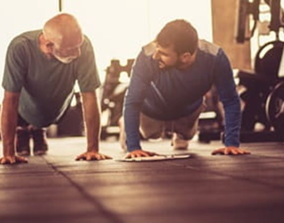 Two people doing pushups in a gym