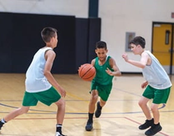 Three kids playing basketball in a gym