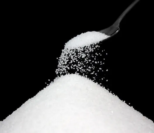 Sugar being poured from a teaspoon