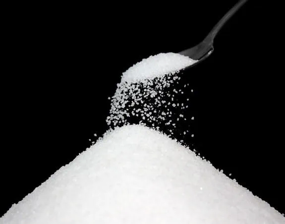 Sugar being poured from a teaspoon