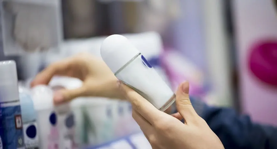 Person choosing between deodorant bottles on a shelf
