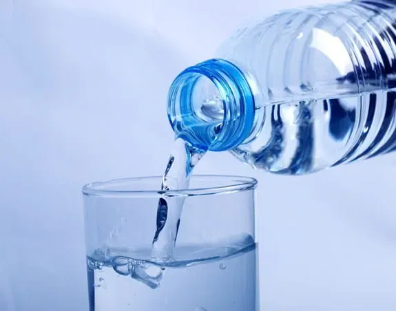 Water being poured from a plastic bottle into a glass