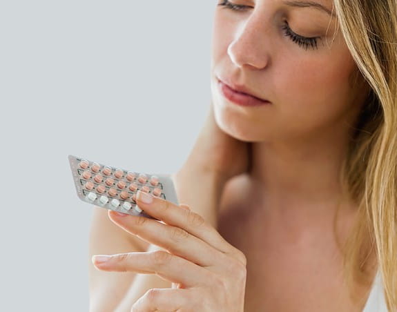 A teenager looking at a pack of birth control pills