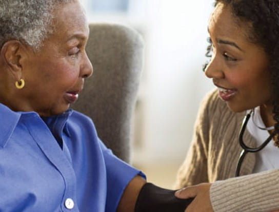 A healthcare worker taking a woman’s blood pressure