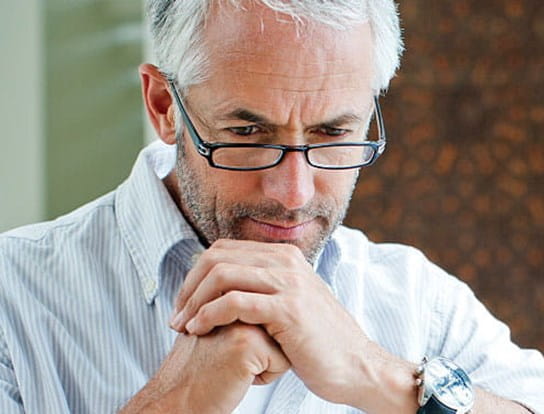 A man with grey hair and eyeglasses playing chess