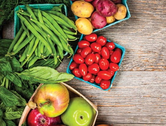 Des pommes, des tomates, des fèves vertes et un oignon sur une table