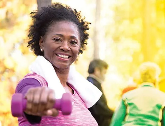 Image of a woman exercising outside with arm weights.