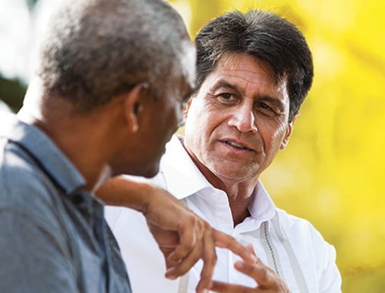 Image of two men talking with one another